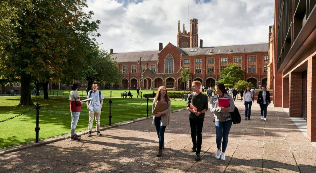 Students walk in groups or converse with one another while at Queen's University Belfast's main campus.