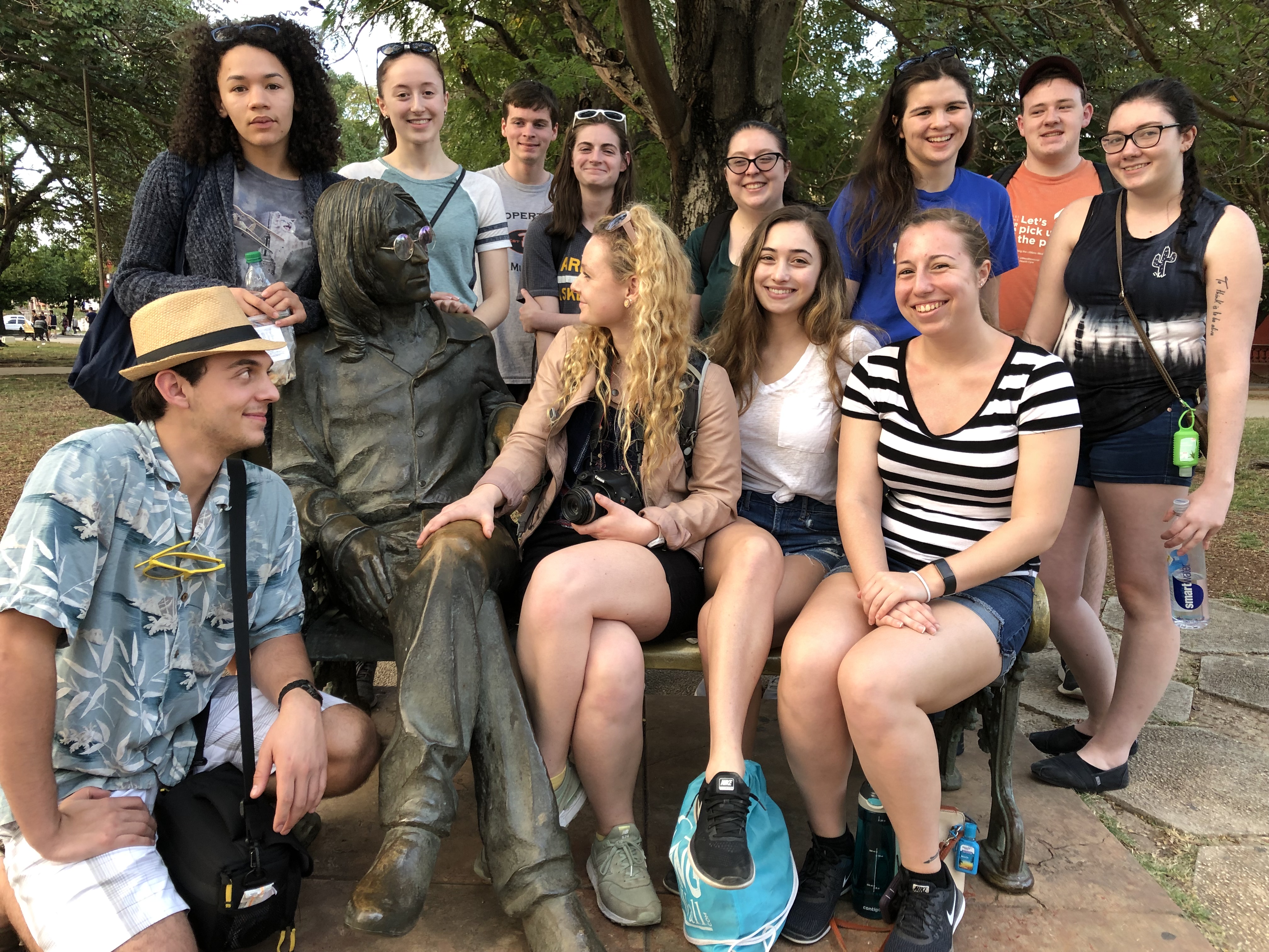 Honors students sit around a statue of John Lennon in John Lennon Park in the neighborhood of Vedado.