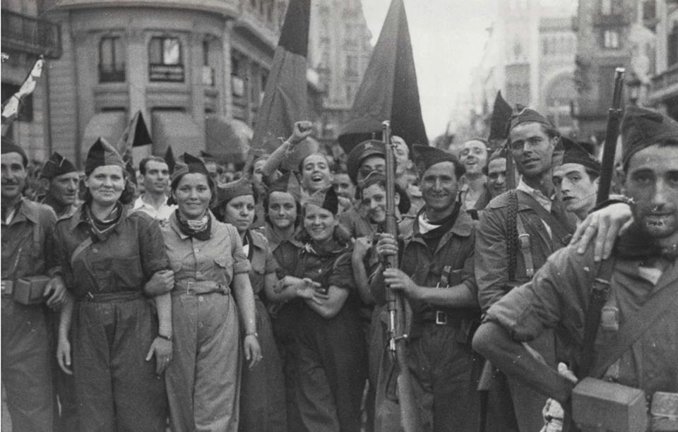 A group of soldiers, male and female, march down a street in Barcelona during the Spanish Civil War.